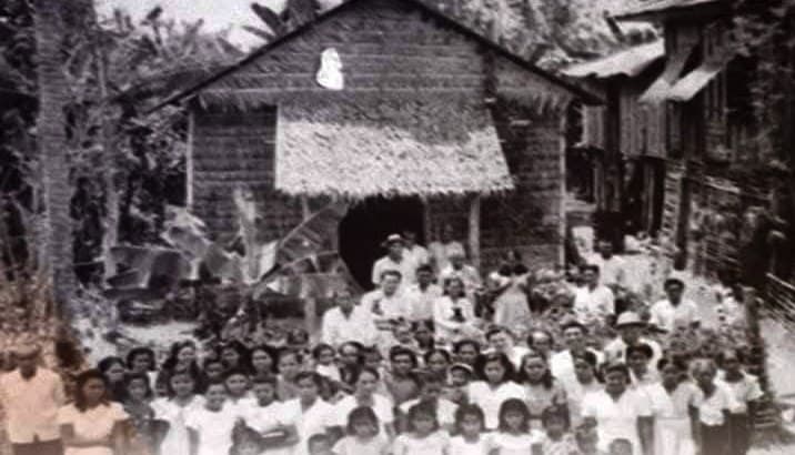 Members gathered in front of Villar Assembly of God, a nipa-roofed church in Sibalom, Antique